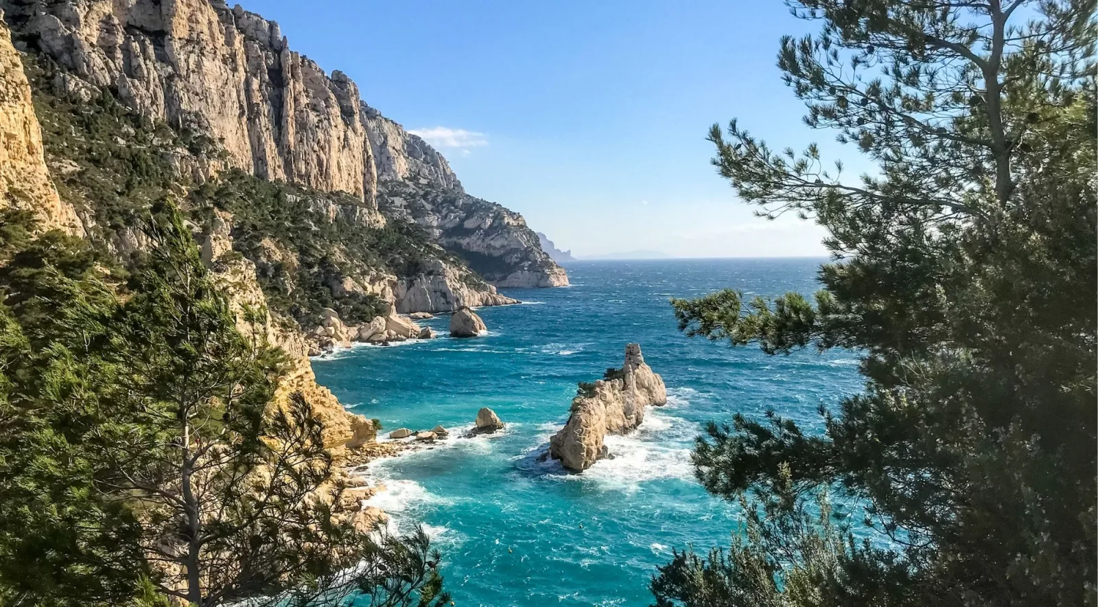 Towering white limestone cliffs and sea stacks above turquoise water in the Calanques