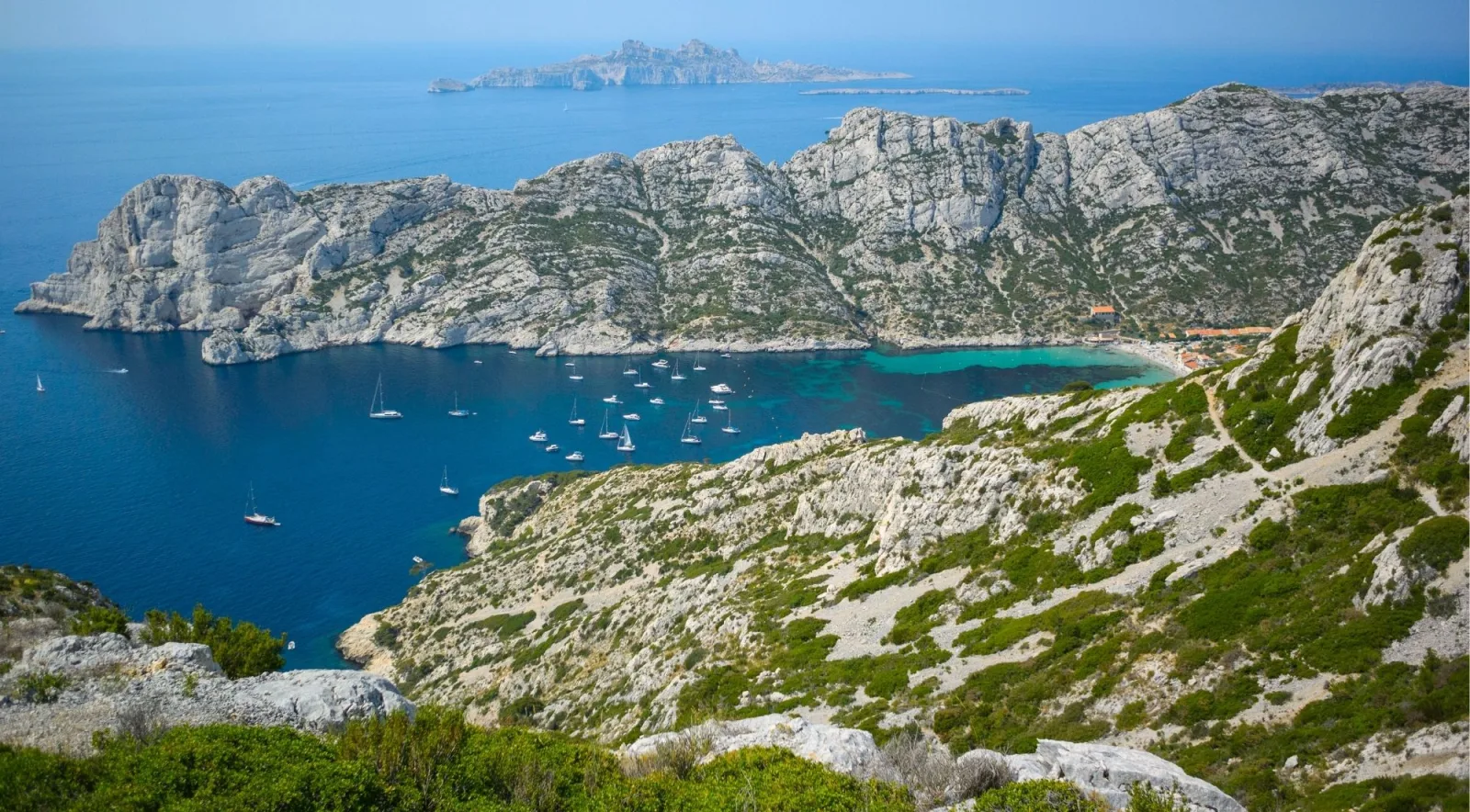 Aerial view of a sheltered Calanques cove with sailboats at anchor and limestone ridges